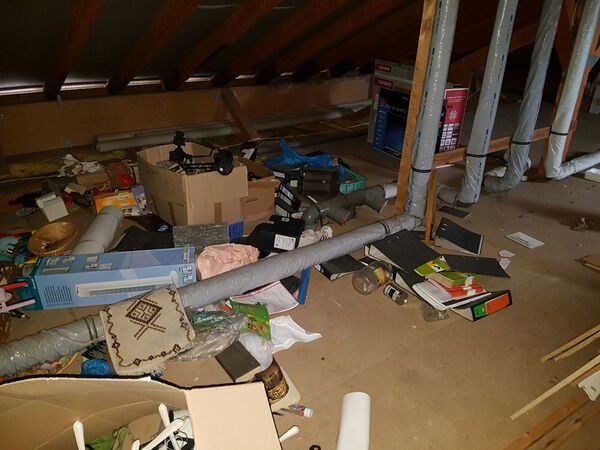 Dachboden mit herumliegenden Kartons, Aktenordnern, Rohren und verschiedenen Gegenständen.