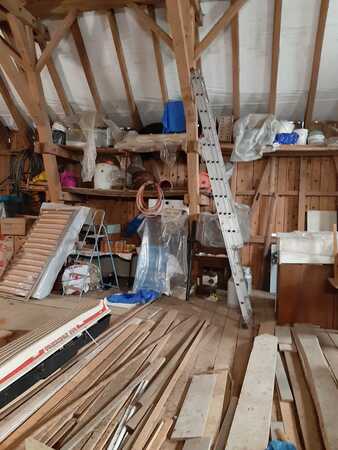 Dachboden mit Holzlatten, Baumaterial, Leiter und Werkzeugen für Renovierung und Ausbau.