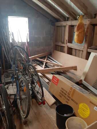 Dachboden mit alten Fahrrädern, Holzlatten, Kartons und einem hängenden Schinken.