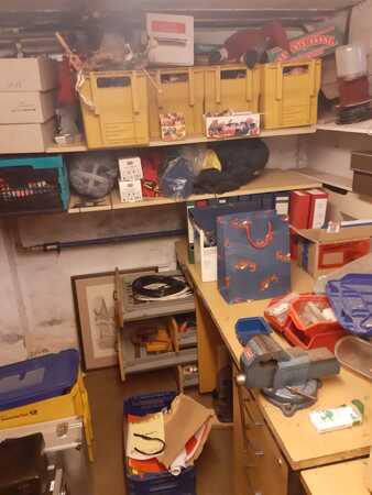 Kellerraum mit Werkbank, Werkzeug, Regalen, Umzugskartons und Aufbewahrungsboxen.